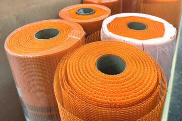 Reinforcing mesh for plaster. Construction mesh in orange color in rolls in a hardware store. Mesh for reinforcing walls in the process of their insulation, rolled up.