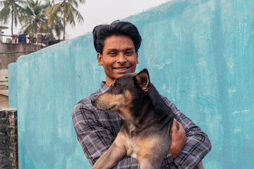 A guy portrait holding his black dog looking at the camera while smiling