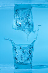 Splash of a glass of water on a blue background. Clean drinking water concept