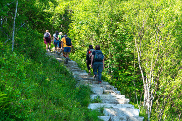 Tourists climb the stairs to the top of the mountain. Norway hiking path in mountains. Lofoten, Reinebringen. hiking tourist climbing Reinebringen stone stairs to mountain peak.
