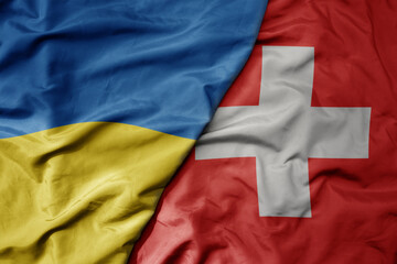 big waving national colorful flag of ukraine and national flag of switzerland .