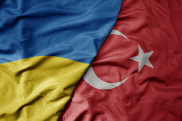Fototapeta premium big waving national colorful flag of ukraine and national flag of turkey .