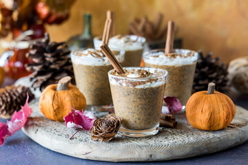 Pumpkin spice chia puddings on a rustic wooden board with fall decorations.