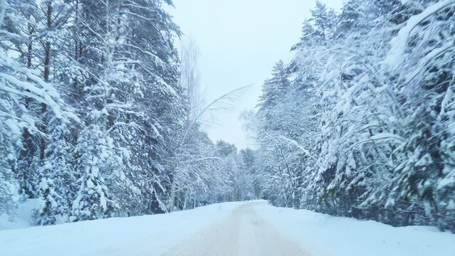 View of snowy country road. Driving on winter forest road after snowfall.