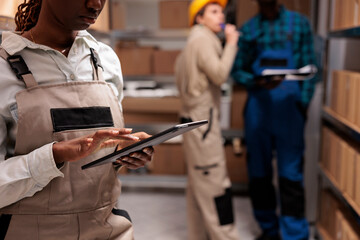 Delivery service warehouse worker monitoring order dispatching process on digital tablet. Shipping...