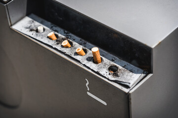 Public stainless steel ashtray with burned cigarettes, Cigarette butts in grey public ashtray 