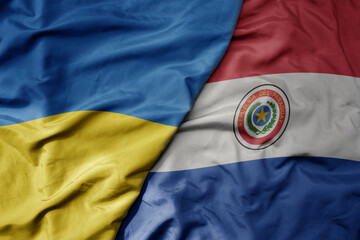 big waving national colorful flag of ukraine and national flag of paraguay .