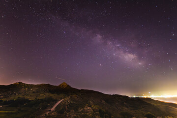 A view of the stars of the Milky Way with a mountain top in the foreground. Night sky nature summer...