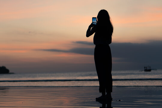 people using smart phone for taking a sunset photo at the beach