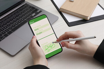 Electronic signature. Woman using stylus and mobile phone at white wooden table, closeup