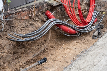 Electric cables in red corrugated pipe are buried underground on the street. electric cable infrastructure installation. Construction site with A lot of supply energy