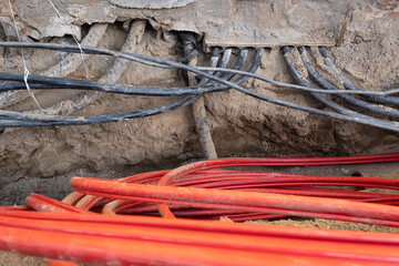 Electric cables in red corrugated pipe are buried underground on the street. electric cable infrastructure installation. Construction site with A lot of supply energy