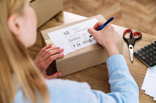 Woman writing address for delivery, filling information on parcel box