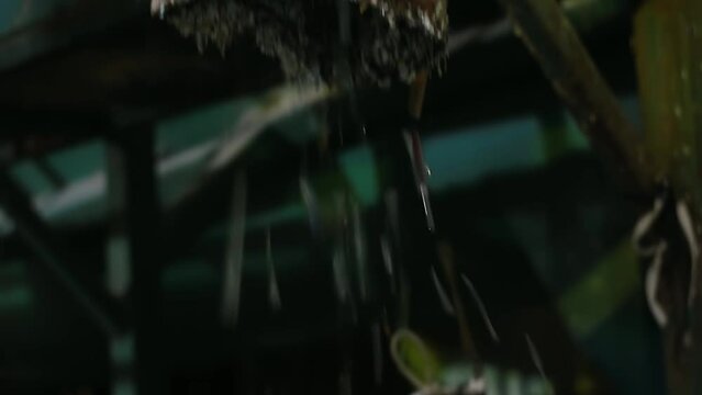 Shredded multi-colored garbage pours out of a rusty metal pipe into a white waste bag for disposal. Inside waste recycling plant, care for the environment