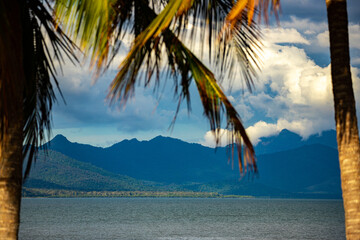 panorama of beautiful, idyllic tropical beach in cardwell, sandy beach with the view of mighty mountains in hinchinbrook island; north queensland, australia