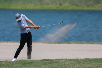 golf player hitting the ball on sand trap