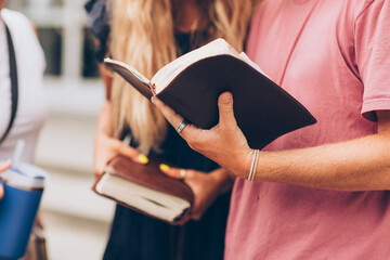 cropped photo of young adults youth talking while holding their bibles leather journal notebook...
