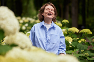 Portrait of an attractive mature woman in summer park. Middle aged brunette female in blue shirt...