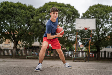 Obraz premium One caucasian teenager stand on basketball court with ball