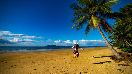 pretty girl in a skirt enjoying a sunny day on the beautiful tropical beach with palm trees, mission beach in north queensland, australia