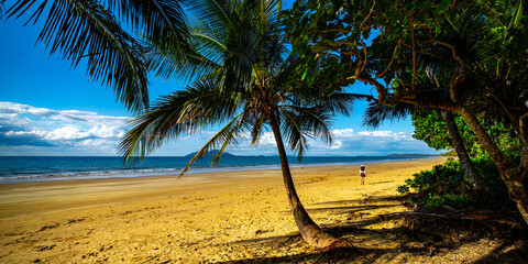 pretty girl in a skirt enjoying a sunny day on the beautiful tropical beach with palm trees, mission beach in north queensland, australia