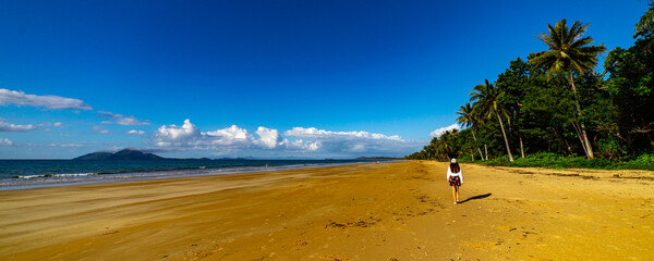 pretty girl in a skirt enjoying a sunny day on the beautiful tropical beach with palm trees, mission beach in north queensland, australia