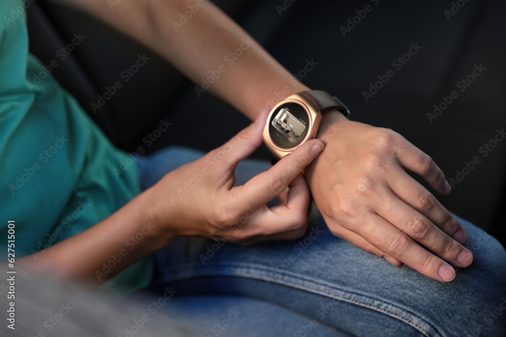 Poster woman checking home security system via smartwatch app in car, closeup. image of room through cctv c