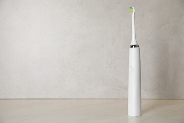 Electric toothbrush on light background, space for text