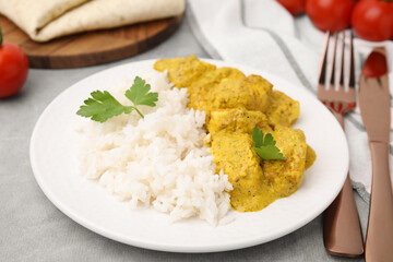 Delicious rice and chicken with curry sauce on light grey table, closeup