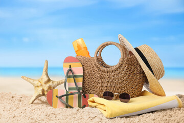 Fototapeta na wymiar Bag with sunscreen and accessories on sunny ocean beach. Summer vacation