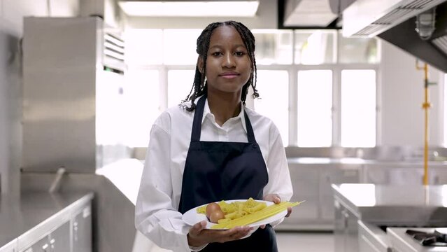 4K tracking view, lifestyles portrait of young smiling African student holding pasta ingredients medium shot, cheerful cooking trainee in uniform apron startup occupation in cooking school concept