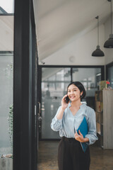 Smiling businesswoman talking on smart phone leaning at office