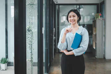 Successful businesswoman standing in creative office and looking at camera. Woman entrepreneur in a coworking space smiling.