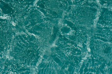 Blue water with ripples on the surface. Defocus blurred transparent blue colored clear calm water surface texture with splashes and bubbles. Water waves with shining pattern texture background.