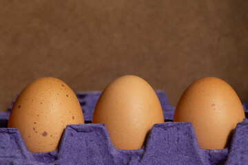 closeup to three single eggs in their maple carton in close focus and background out of focus,with one distinctive spotted egg
