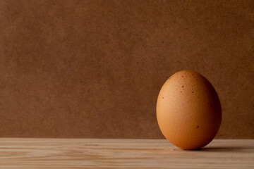 a spotted egg standing on the right side with a wooden surface and background, giving a simple and rustic style with a large space for text