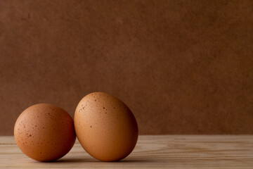 two eggs placed on the left side with stains, on top of wood and darker wood background giving it a rustic style, with space for text
