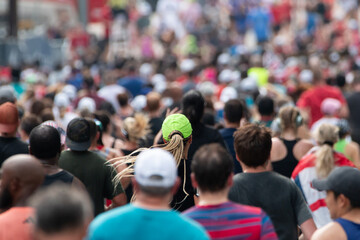 Lone neon green hat stands out in massive crowd of runners at major 10K event.