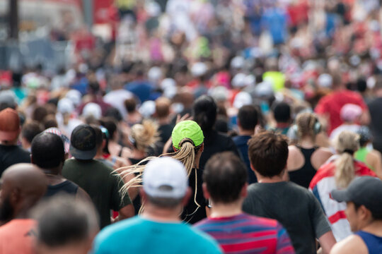 Lone neon green hat stands out in massive crowd of runners at major 10K event. - Powered by Adobe