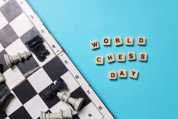 Inscription words of World Chess Day on wooden cubes with chess board and chess figures on blue...