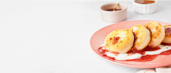 Plate of tasty cottage cheese pancakes, sour cream and raspberry jam on light background with space...