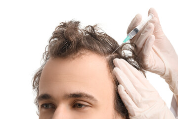 Fototapeta premium Young man receiving injection for hair growth on white background, closeup