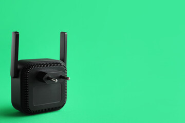 Black WiFi repeater on green background