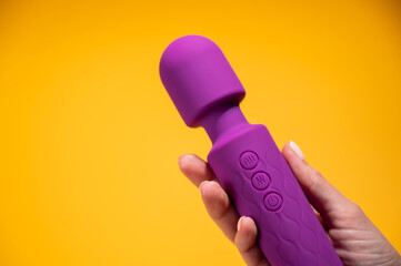 Woman holding purple vibrator on orange background. Copy space. 