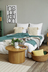 Interior of bedroom with cozy bed and houseplant on coffee table