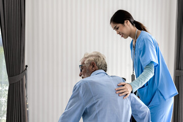 Smiling nurse working and taking care of eldery man in nursing home care  - obrazy, fototapety, plakaty