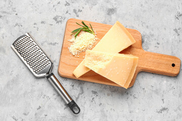 Wooden board with pieces of tasty Parmesan cheese on grunge background