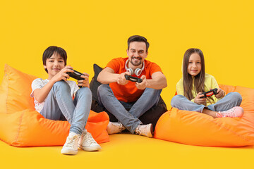 Father with his little children playing video game on yellow background