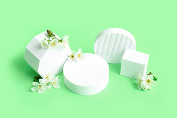 Decorative podiums and white flowers on green background