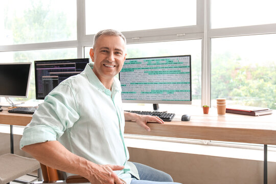 Mature male programmer sitting in light office at his workplace